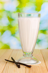 Vanilla milk shake on wooden table on bright background