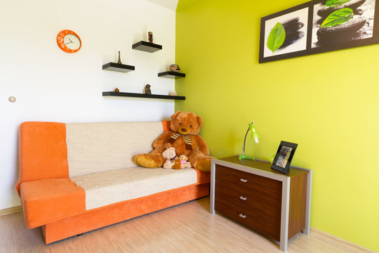 Kids white and green bedroom with orange sofa