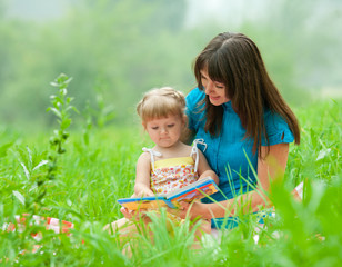 mother and daughter reading book together  outdoor