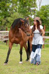 A beautiful  girl in a cowboy hat with a horse