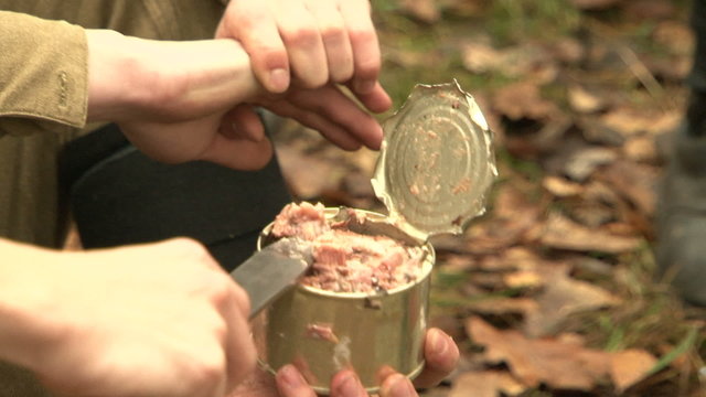 Soldiers with a knife opens canned food