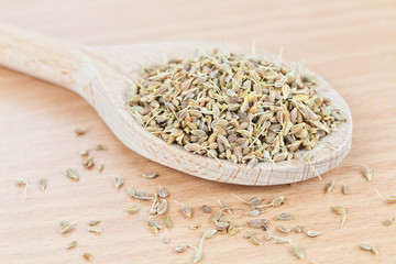 Wooden spoon filled with dry aniseed on the kitchen board