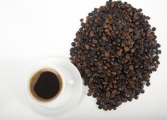 Cup of black coffee on a saucer on roasted coffee beans  
