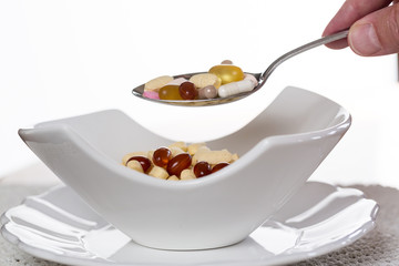 Spoon of vitamins over bowl of tablets
