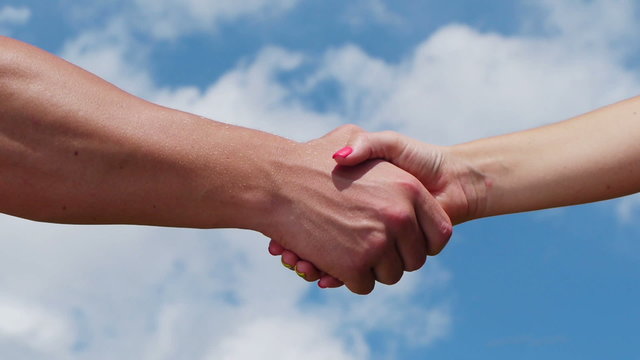 A man and woman shaking hands on blue sky background