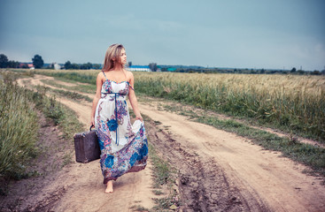 walking girl with old suitcase on the road