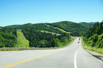 Downhill road with mountains and coniferous trees