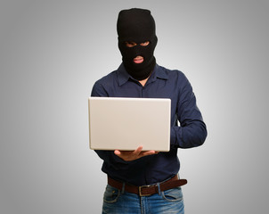 young male thief holding laptop
