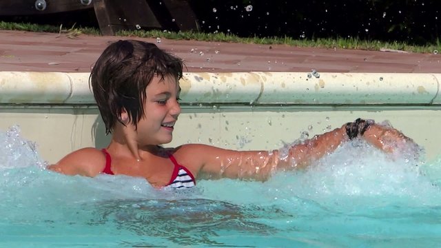 young girl splashing in the pool