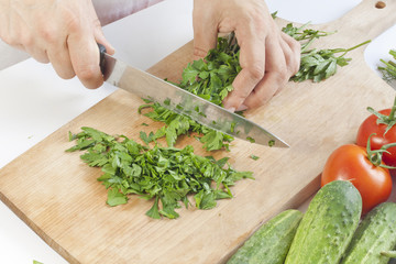 Cook in the kitchen at work cutting parsley