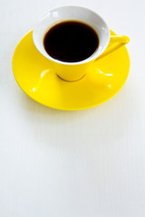 Black coffee in yellow cup and saucer