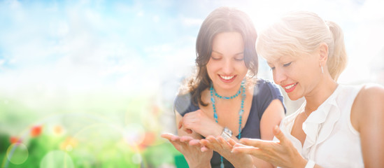 Two women mother and daughter sitting at park and having fun tog