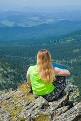 Naklejka na ściany i meble Woman sitting on mountain peak