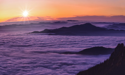mountain sunset above clouds