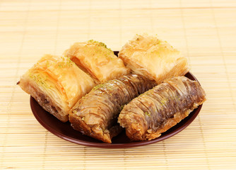Sweet baklava on plate on bamboo mat