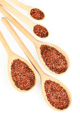 flax seeds in wooden spoons on white background close-up