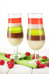 fruit jelly in glasses, berries and mint on wooden table
