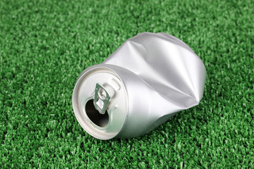 crumpled empty can on grass.