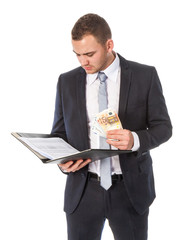 Businessman with money is reading some papers; isolated on white