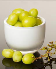 White glass bowl full of green grapes