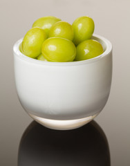 White glass bowl full of green grapes
