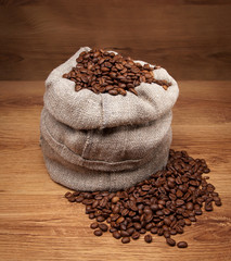 Canvas bag with coffee beans on rustic table with wooden texture