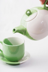 Tea being poured into tea cup isolated on a white background