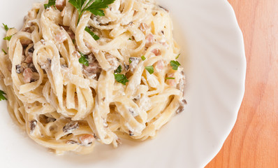 Spaghetti . Fettuccine carbonara in a white bowl, garnished with