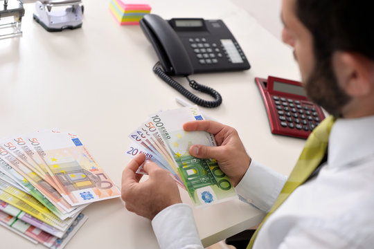 Gesch&auml;ftsmann im B&uuml;ro z&auml;hlt Euroscheine
