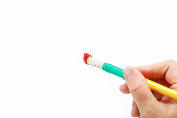 Female hand holding brush with red paint, isolated over white.
