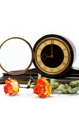 Dry roses and antique wooden table clock on a white background.