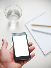 Man using smartphone, cup of water and notebook on the backgroun