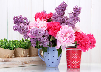 spring flowers in cups on table on white wooden background