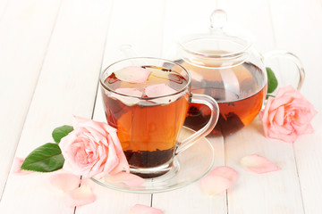 teapot and cup of tea with roses on white wooden table