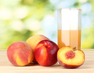 Ripe peaches and juice on wooden table on natural background