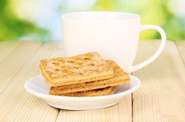 Cup of tea and cookies on wooden table on bright background