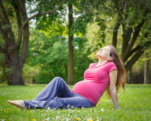 Naklejka na ściany i meble Beautiful pregnant woman in the park
