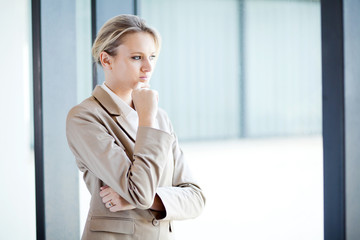 thoughtful young businesswoman looking outside of window