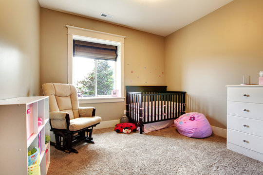 Nursing room for baby girl with brown wood crib.