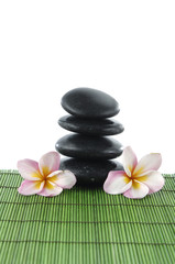 Obraz na płótnie Canvas Balanced Zen stonesw with two frangipani and on green mat