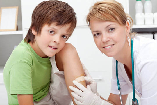Doctor putting adhesive bandage on boy's wound