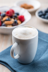 Cup of cafe au lait and granola with fruits in background