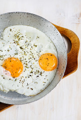 Fried eggs with spice on the frying pan