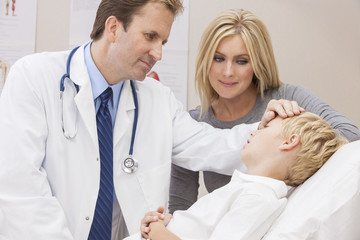 Obraz premium Male Doctor Examining Boy Child With Mother