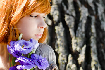 Young beautiful red hair woman holding purple chinese rose