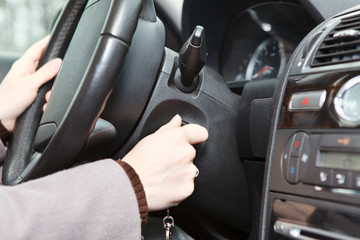 Female hand starting a car engine with ignition key