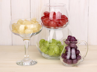 Color candies in glasses on wooden background