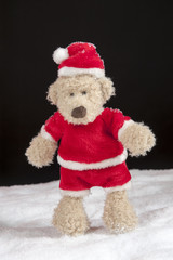 teddy bear in christmas clothes stiandng in the snow