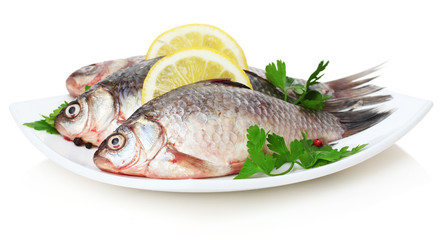 Fresh fishes with lemon and parsley on plate isolated on white