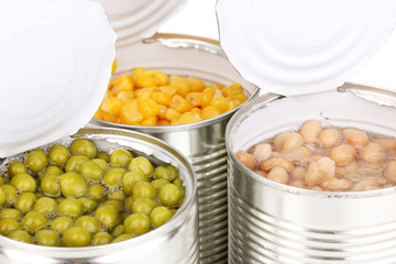 Open tin cans of corn, beans and peas isolated on white